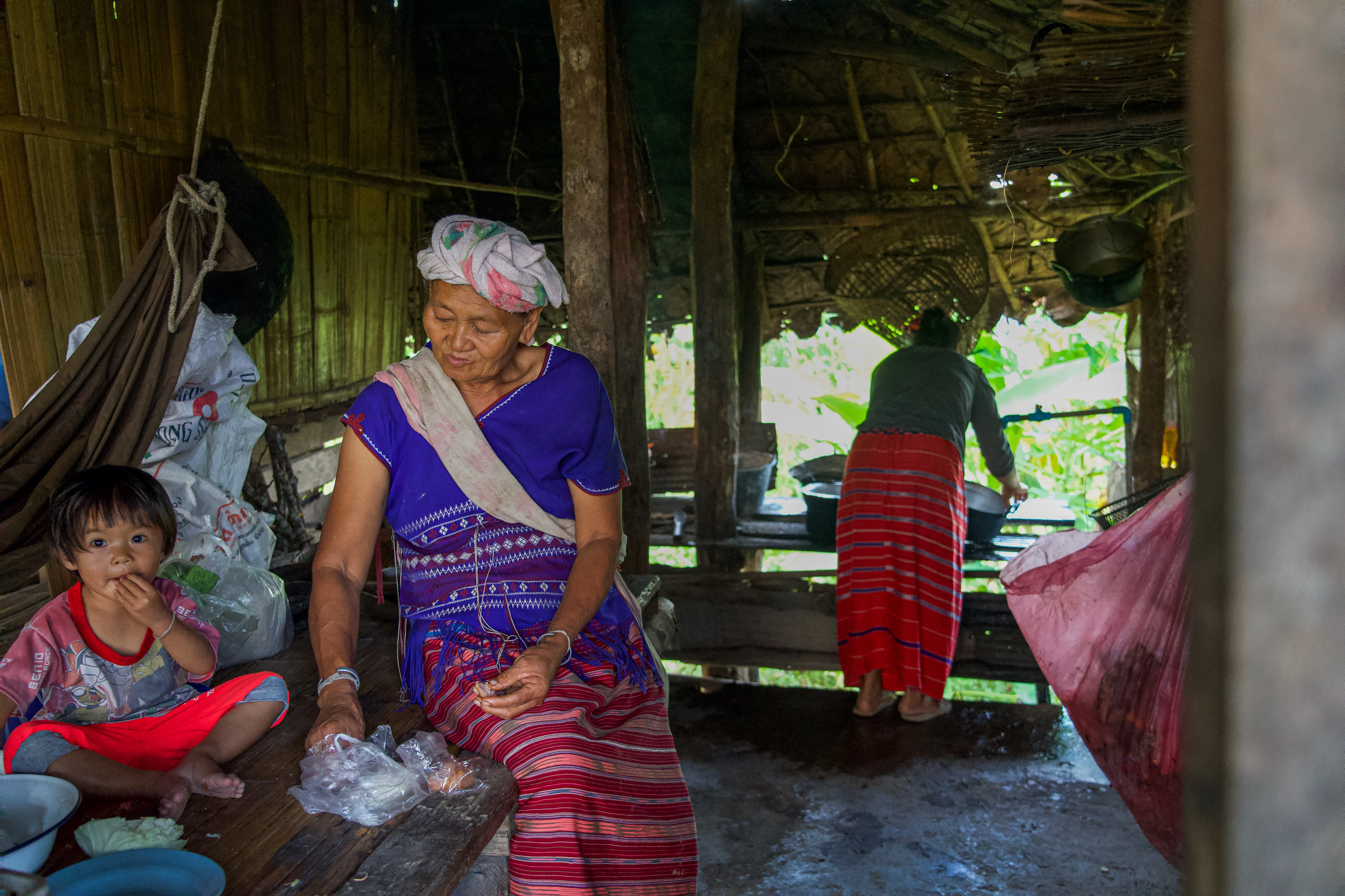Grandmother and child in a stilt-house kitchen in northern, Thailand