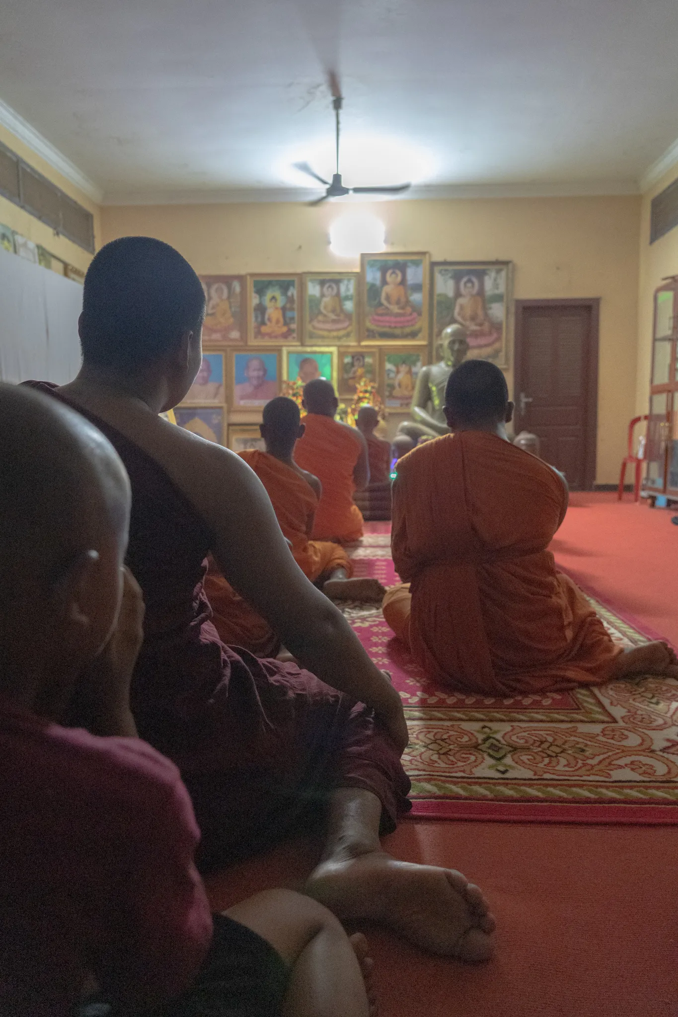 Evening prayers beneath rows of Buddha images, Cambodia
