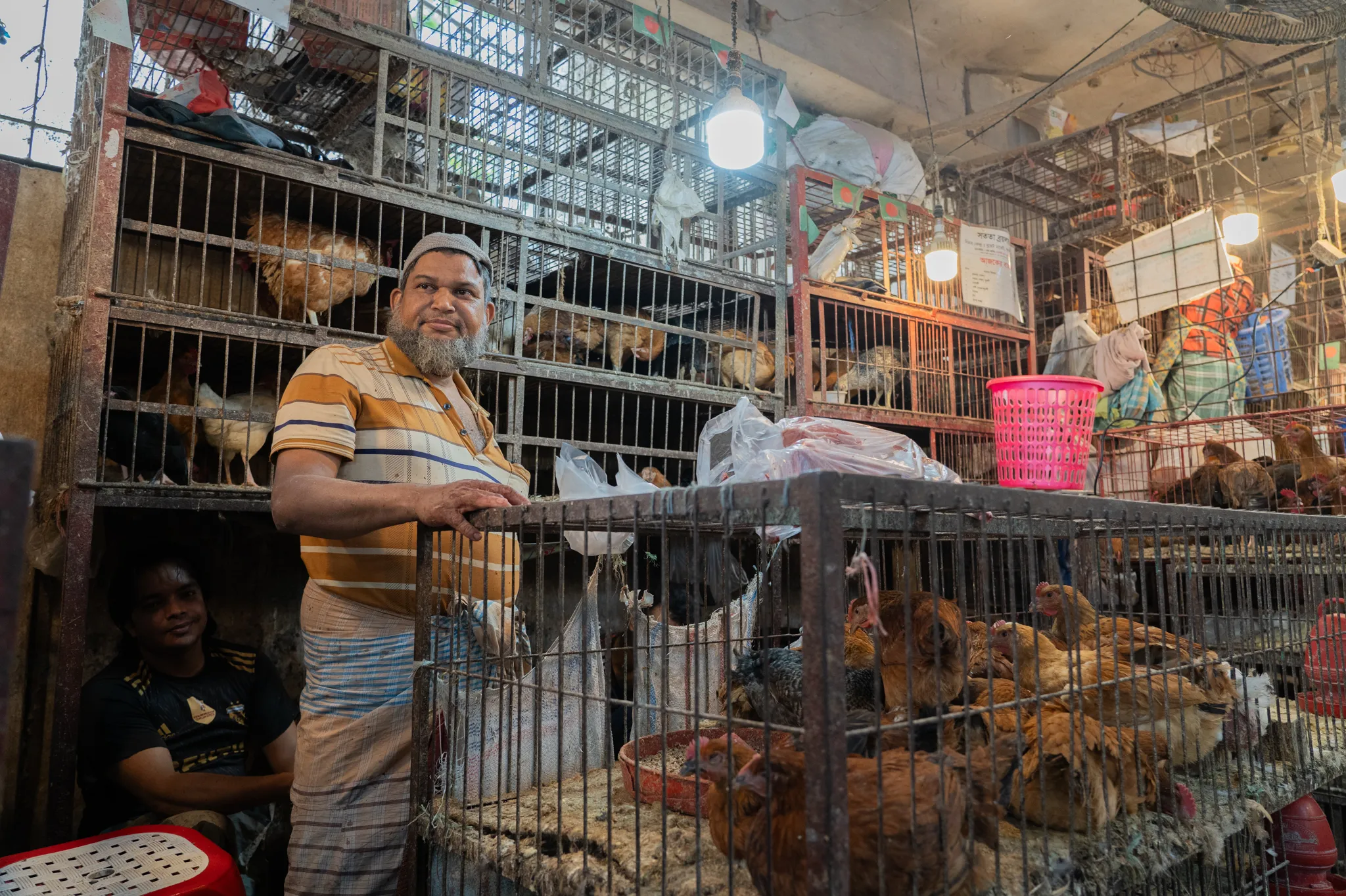 Portrait of a chicken seller among his cages, Bangladesh