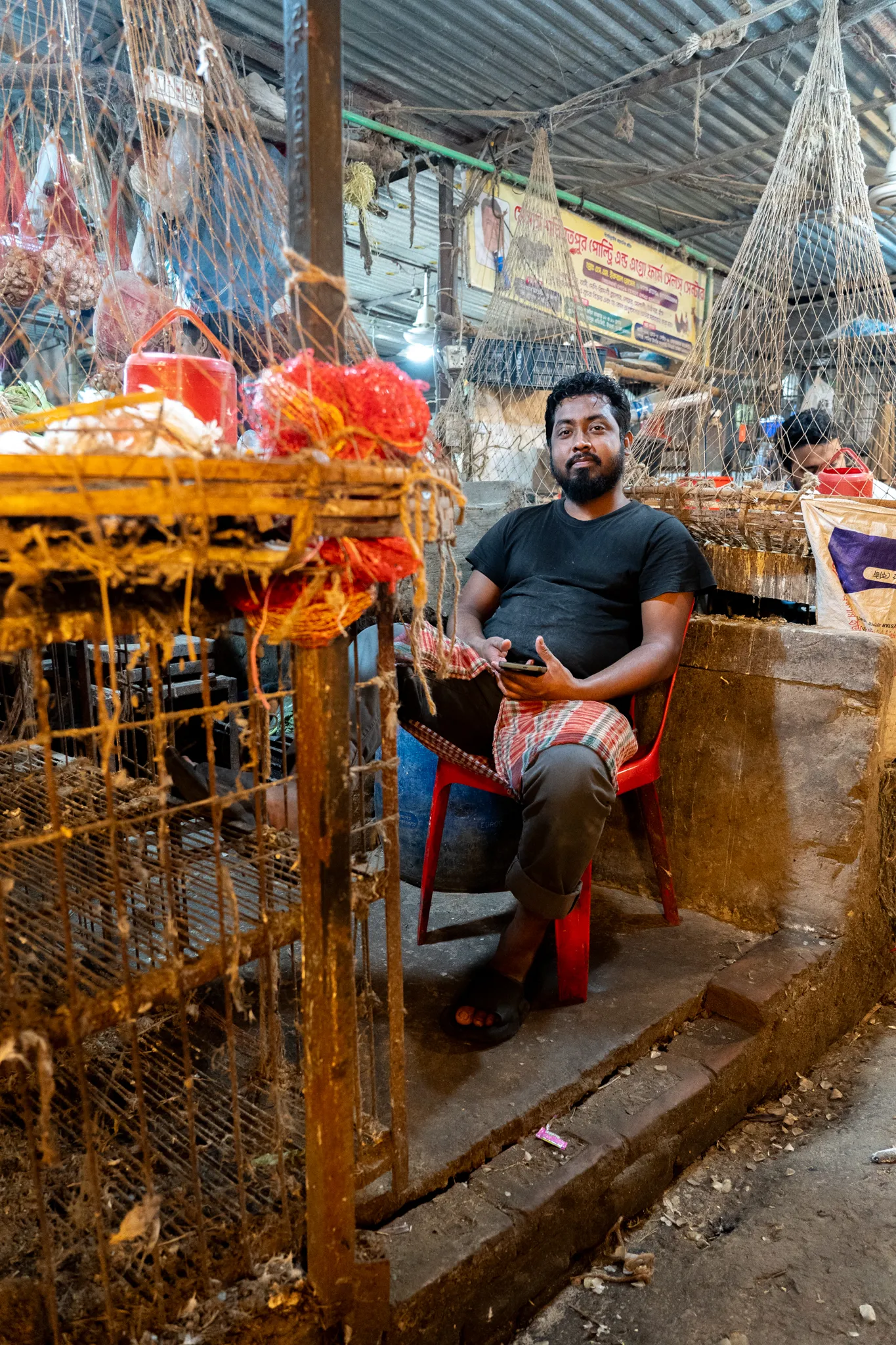 Portrait of a vendor beside cages, Bangladesh