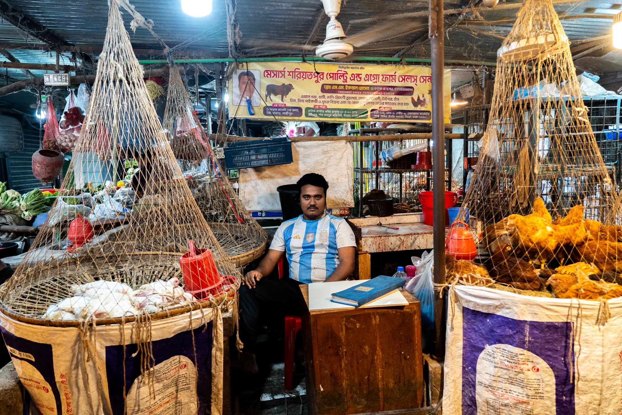 Poultry seller minding his stall, Bangladesh