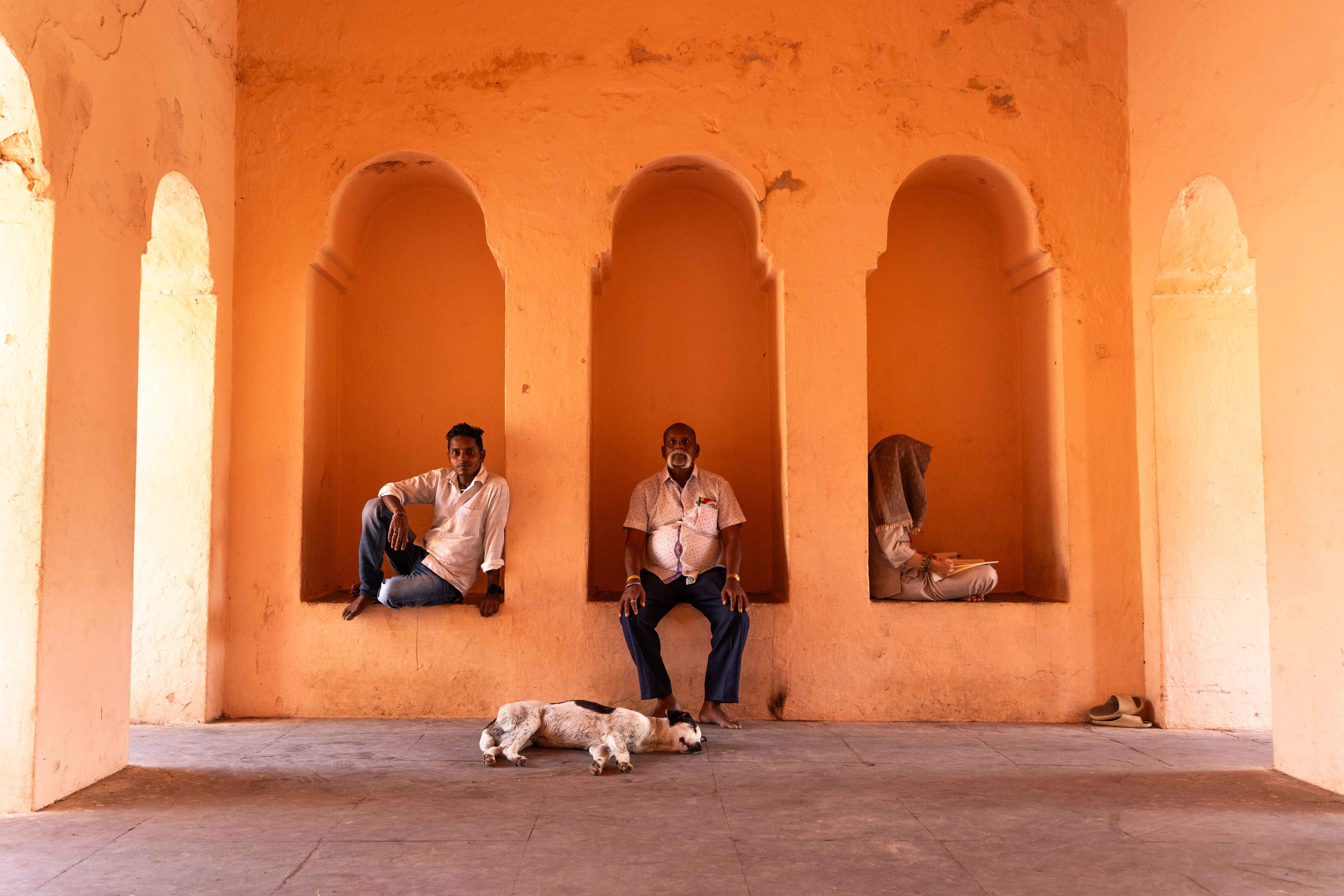 Three people and a sleeping dog in the archways in Bodh Gaya, India