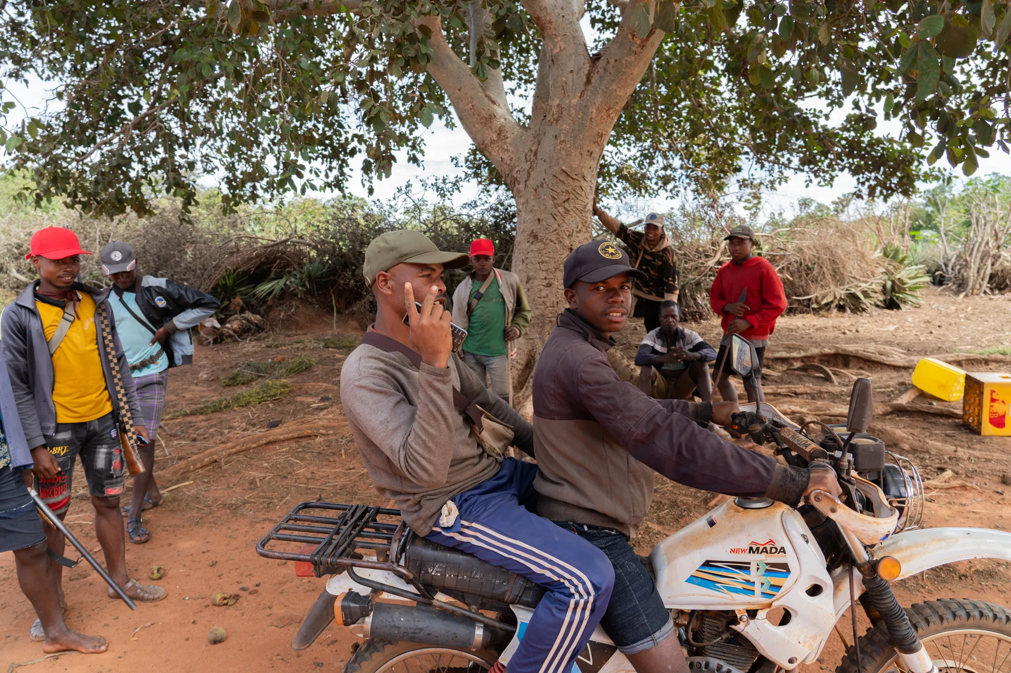 Bara men gathered under a tree with a motorbike, Madagascar