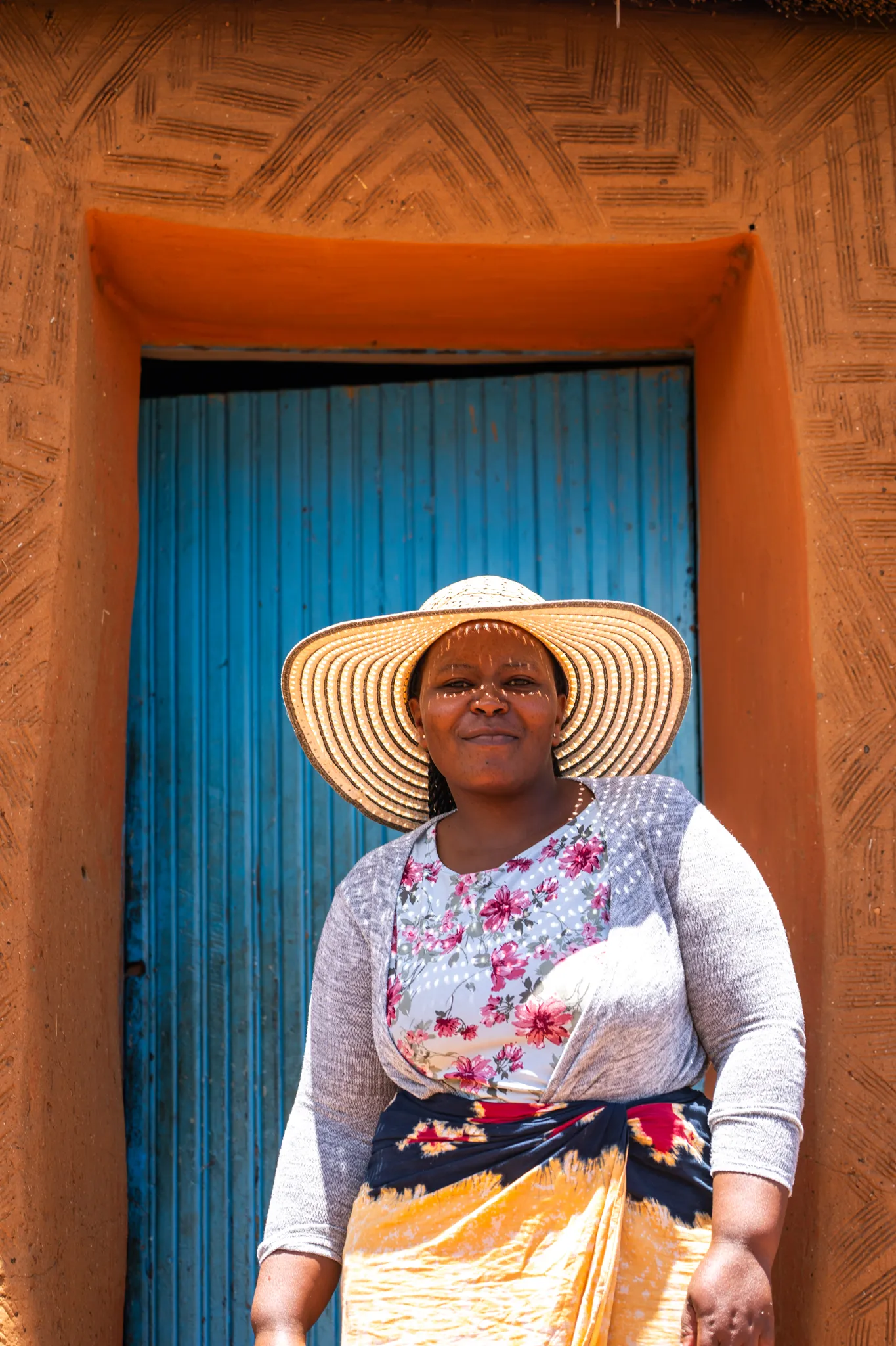 Woman in straw hat framed by a painted doorway, Lesotho