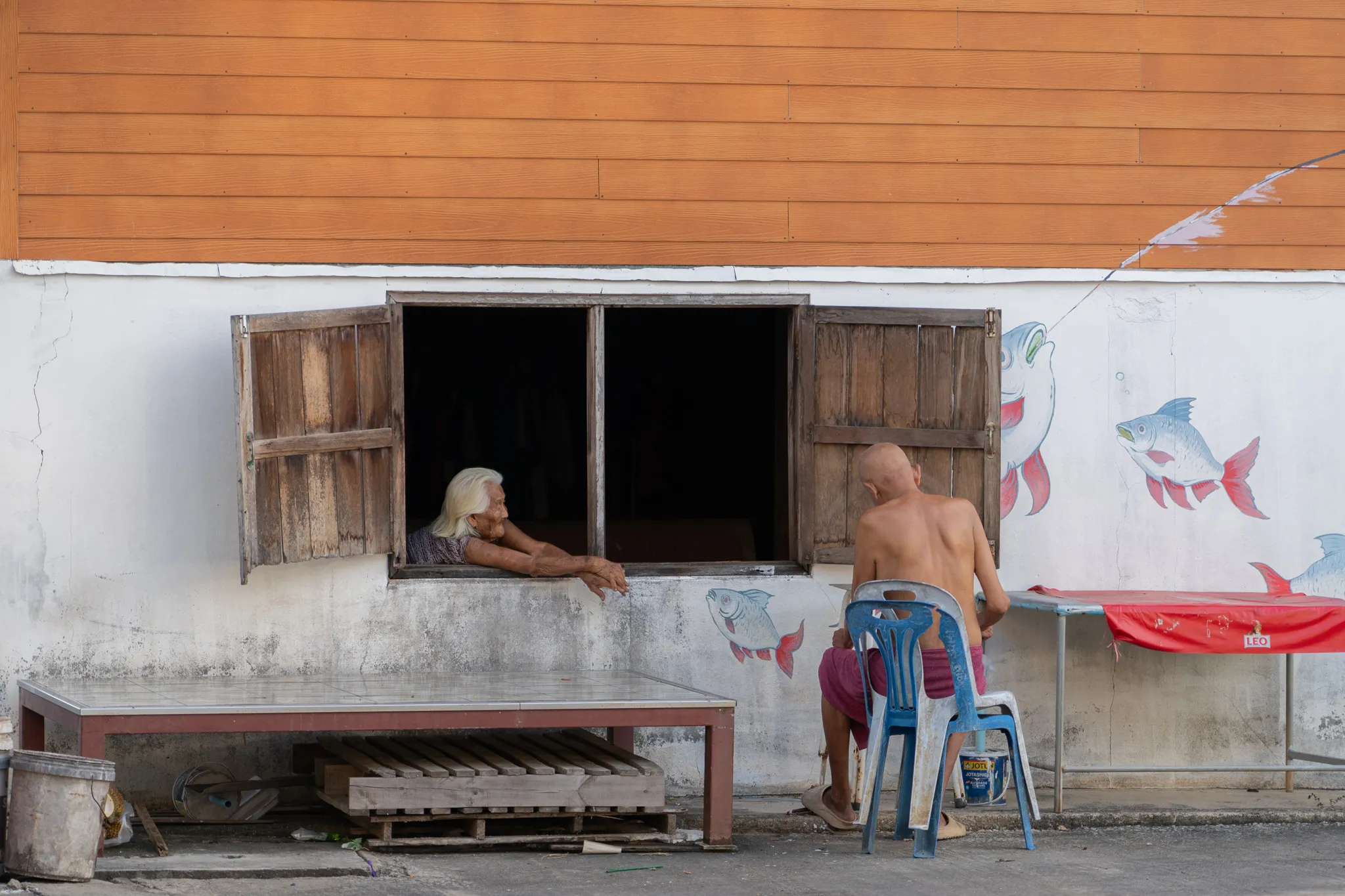 Chatting through a window painted with fish, Thailand