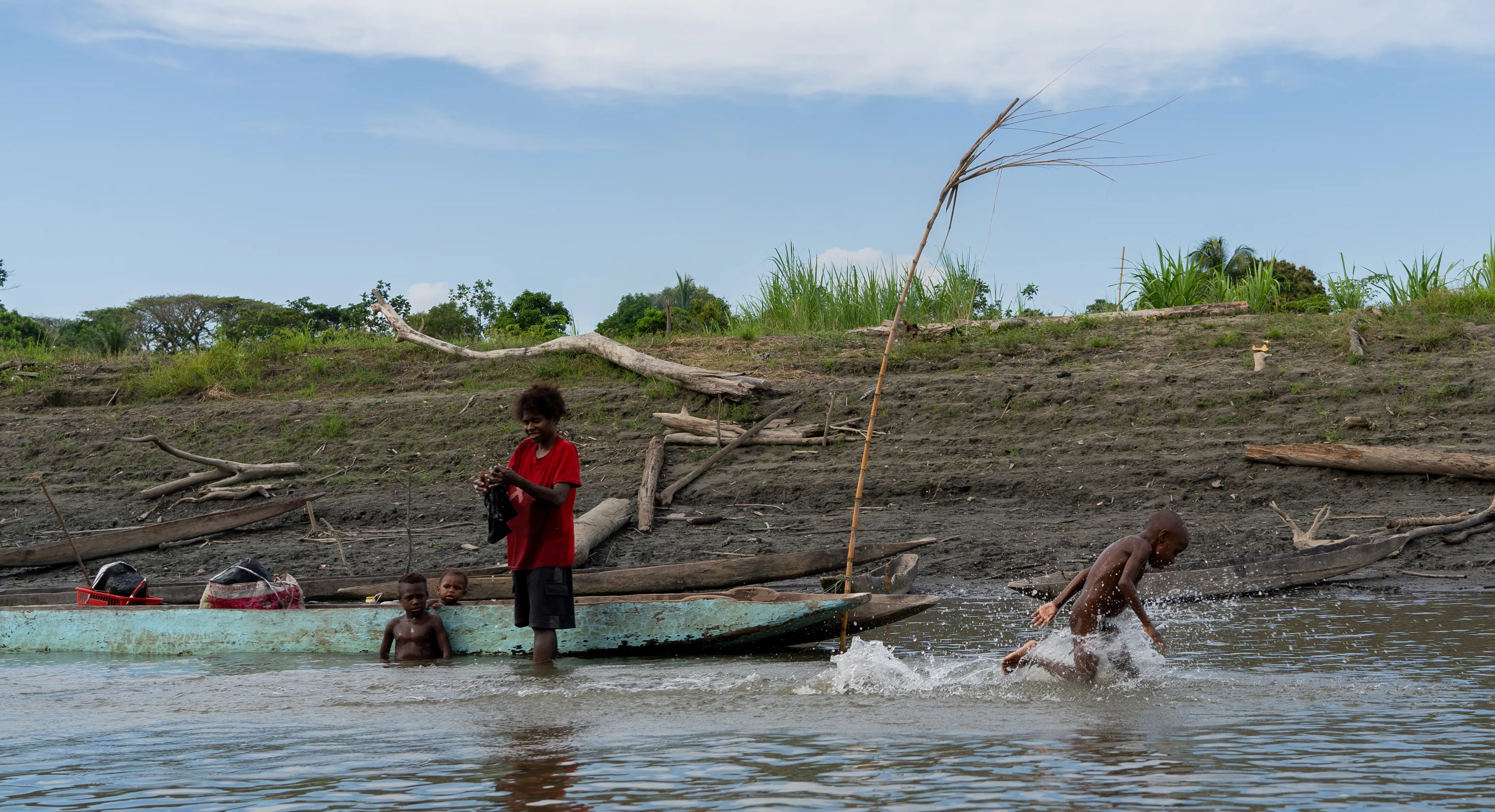 Kids playing along the riverbank by dugout canoes, Papua New Guinea