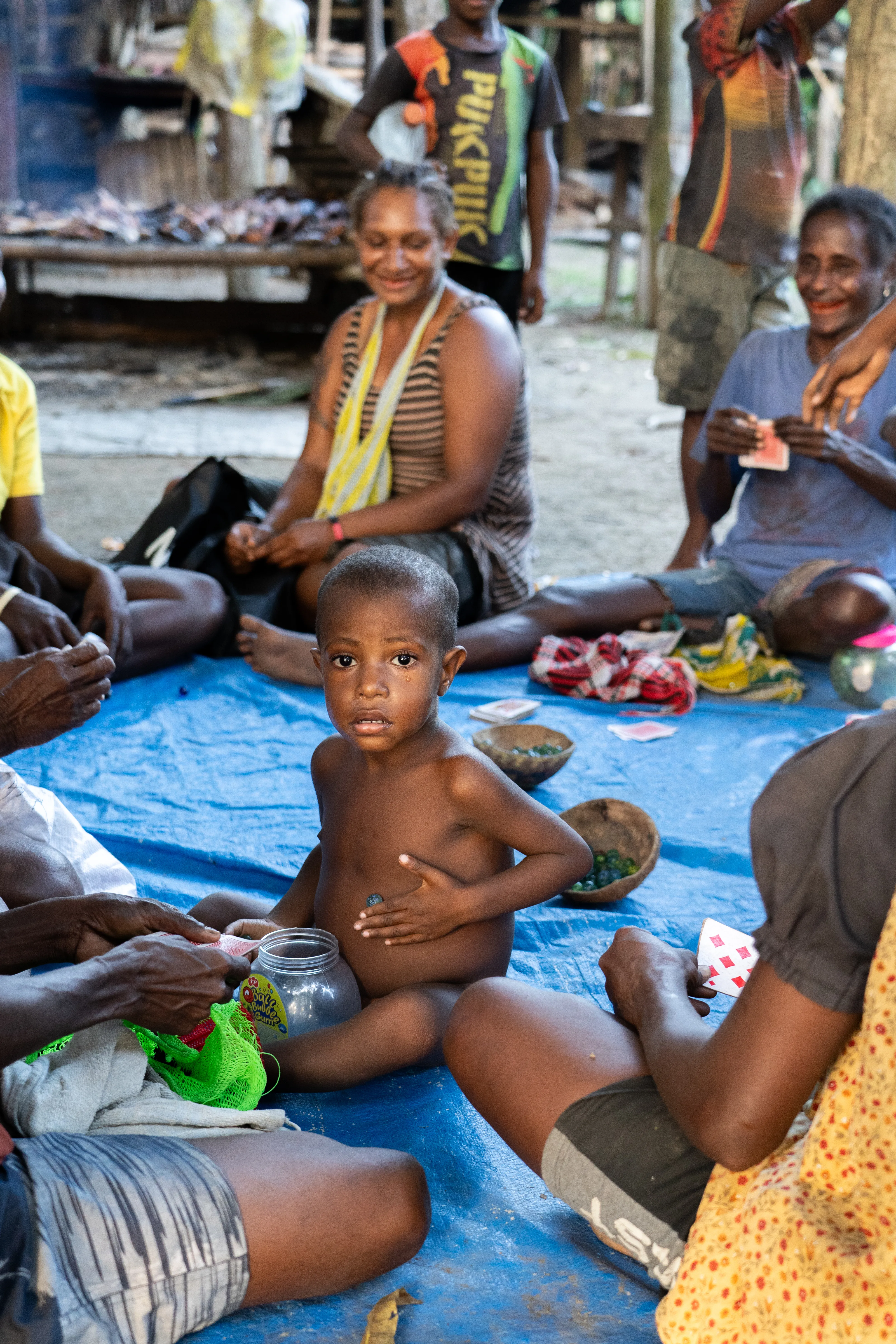 Boy sitting with marbles and playing cards, Papua New Guinea