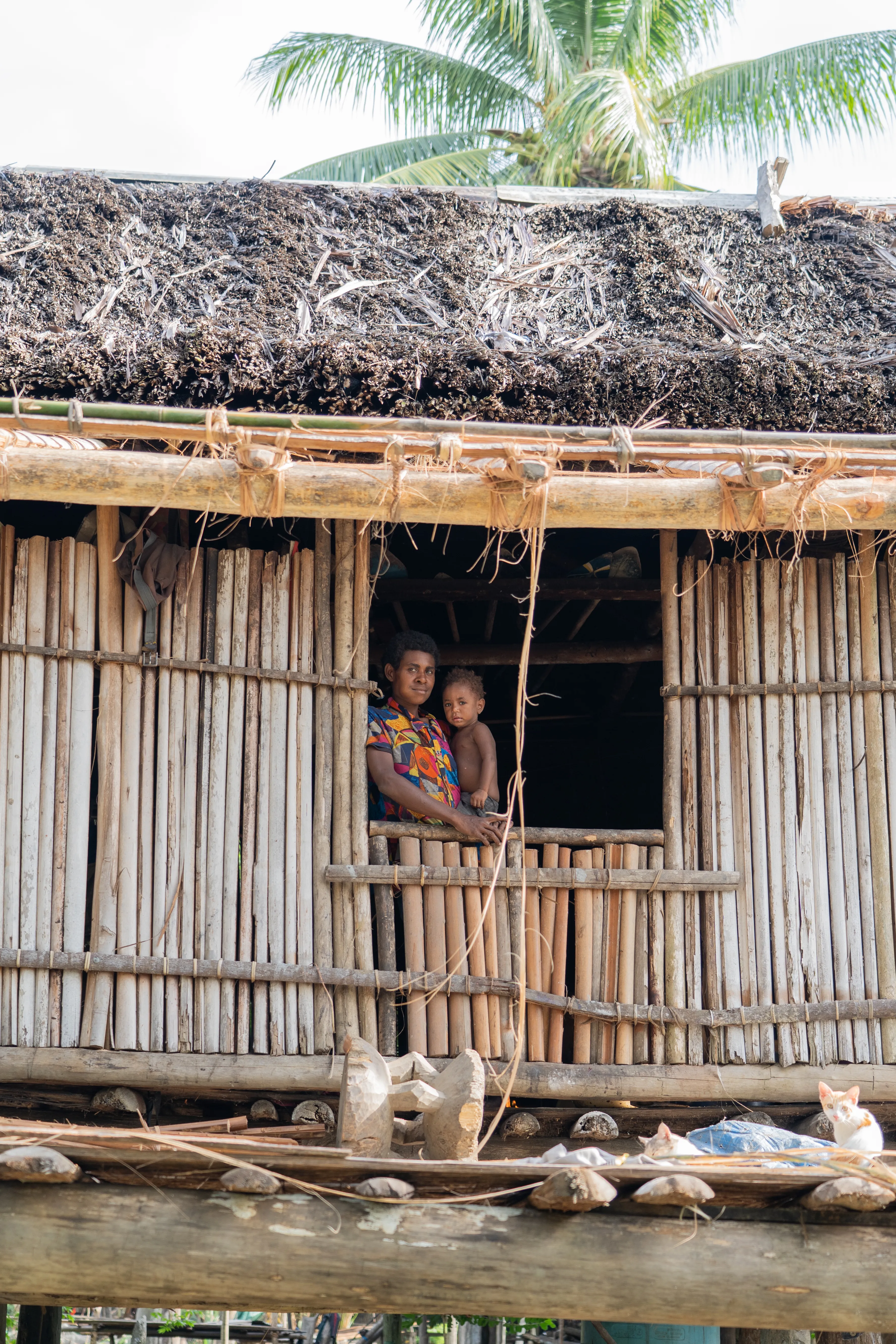 Mother and child in a stilt house window, Papua New Guinea