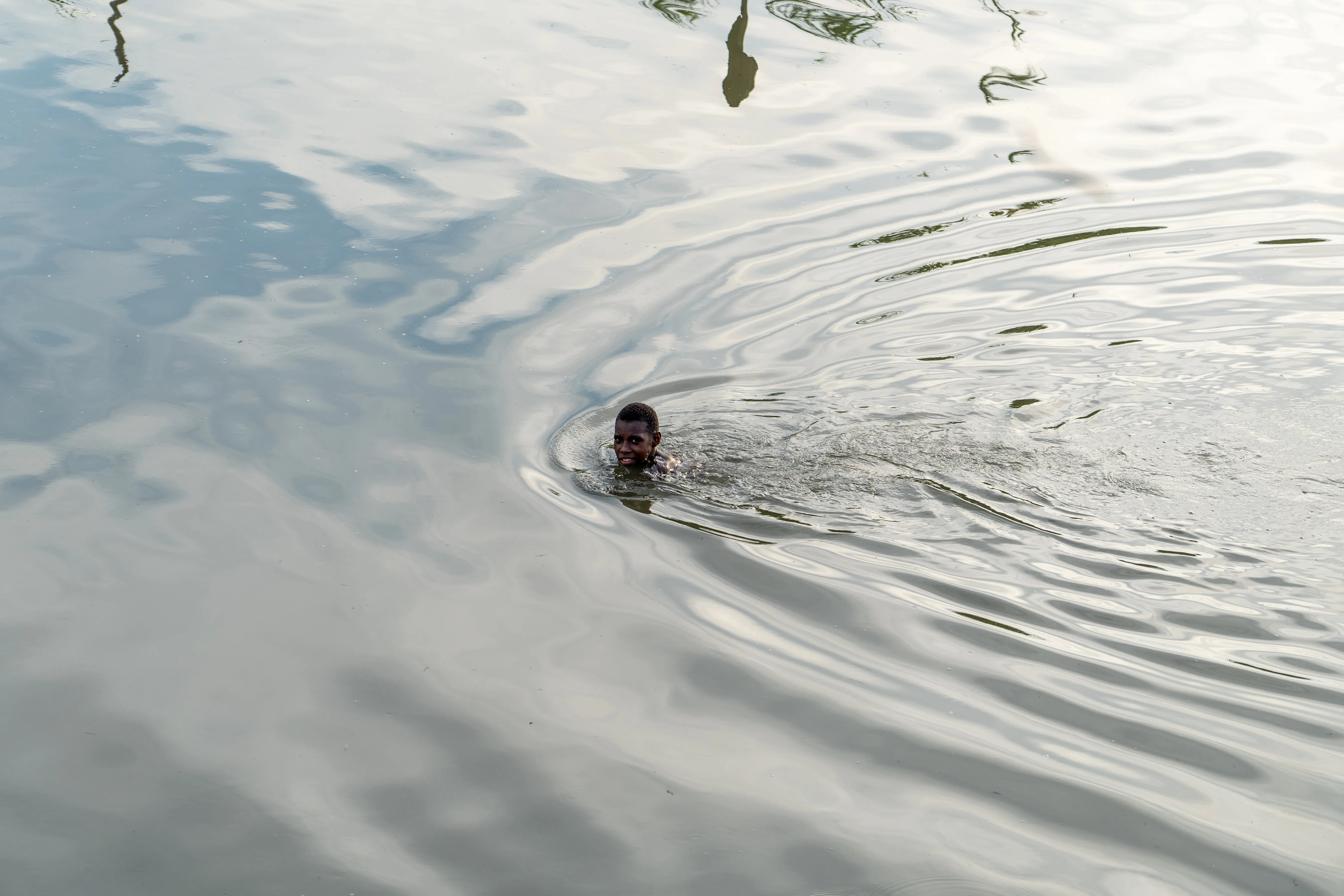 Boy swimming in still river water, Papua New Guinea
