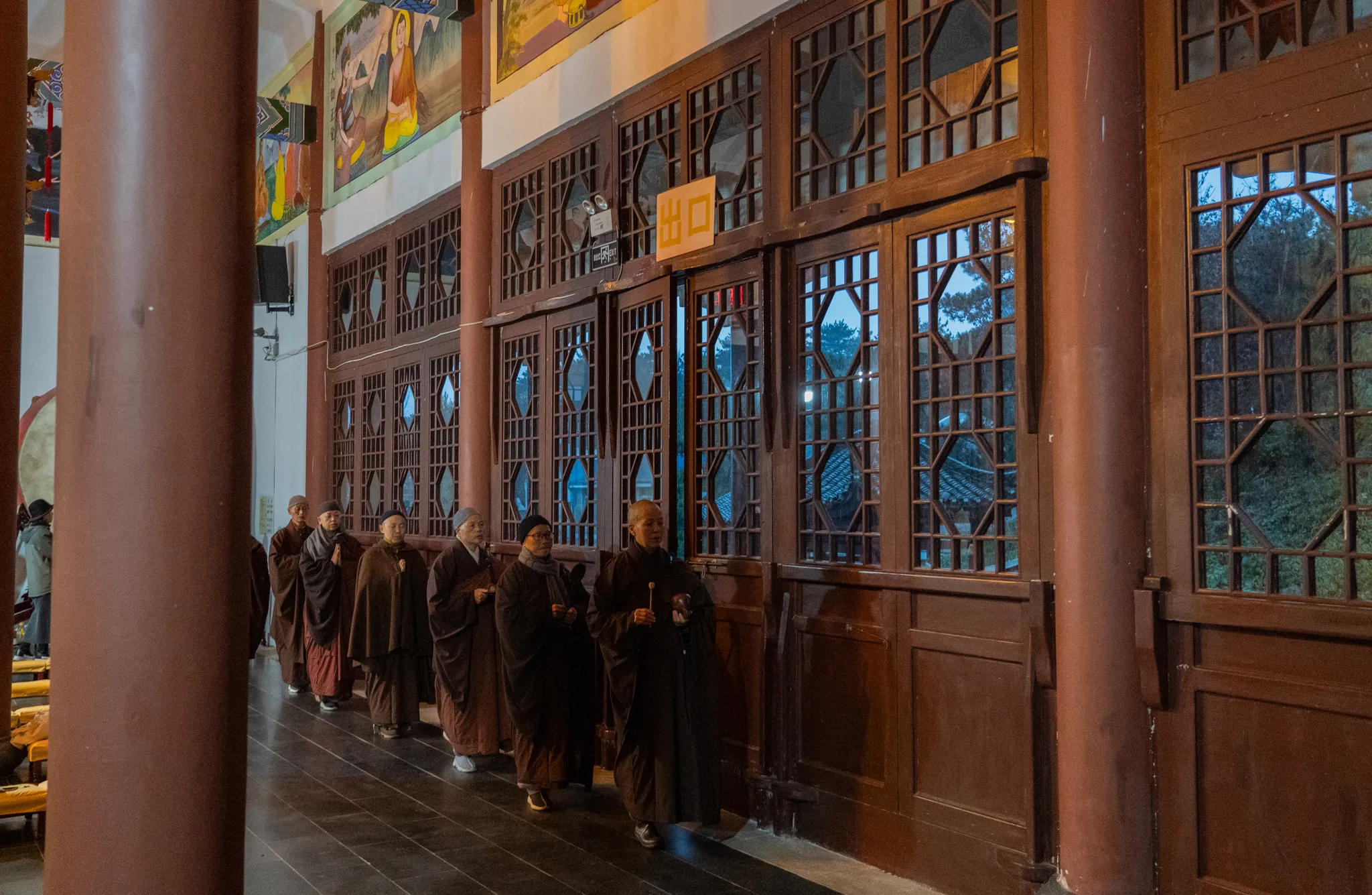 Monks filing past carved temple doors at dusk, China