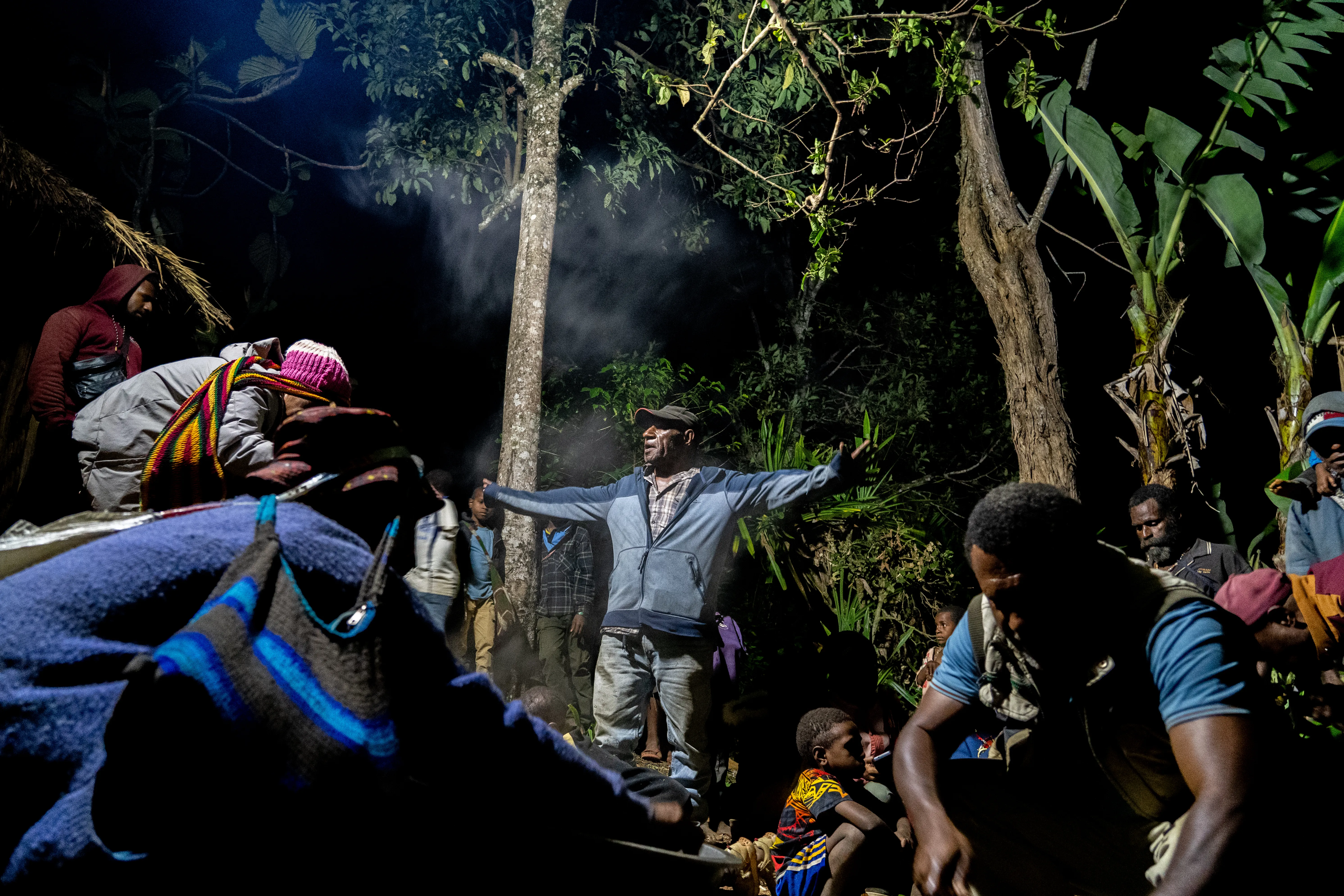 A 'mumu' at night, women cut up a cooked pig to hand out, Papua New Guinea