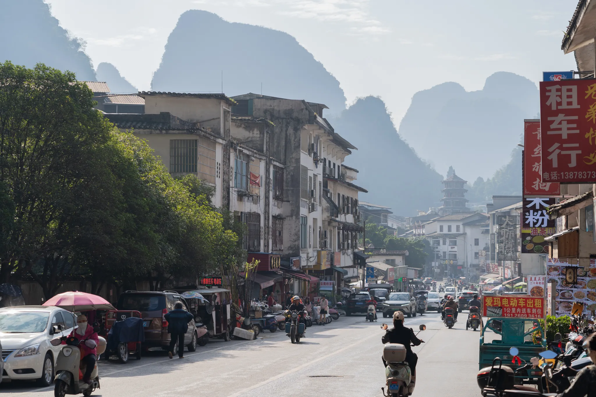 Street traffic beneath limestone peaks and a pagoda in Yangshuo, China