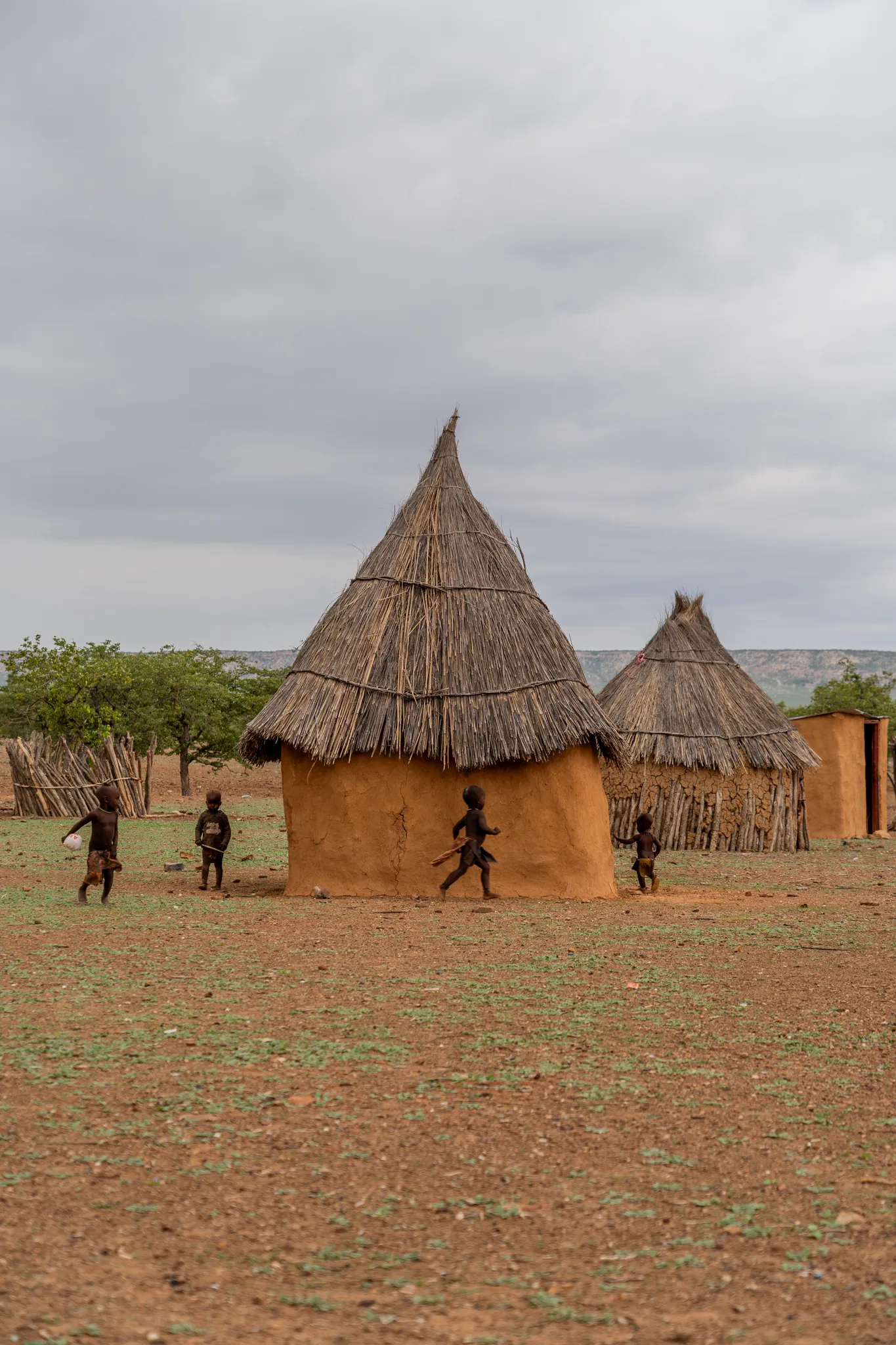 Children playing outside a thatched home, Namibia