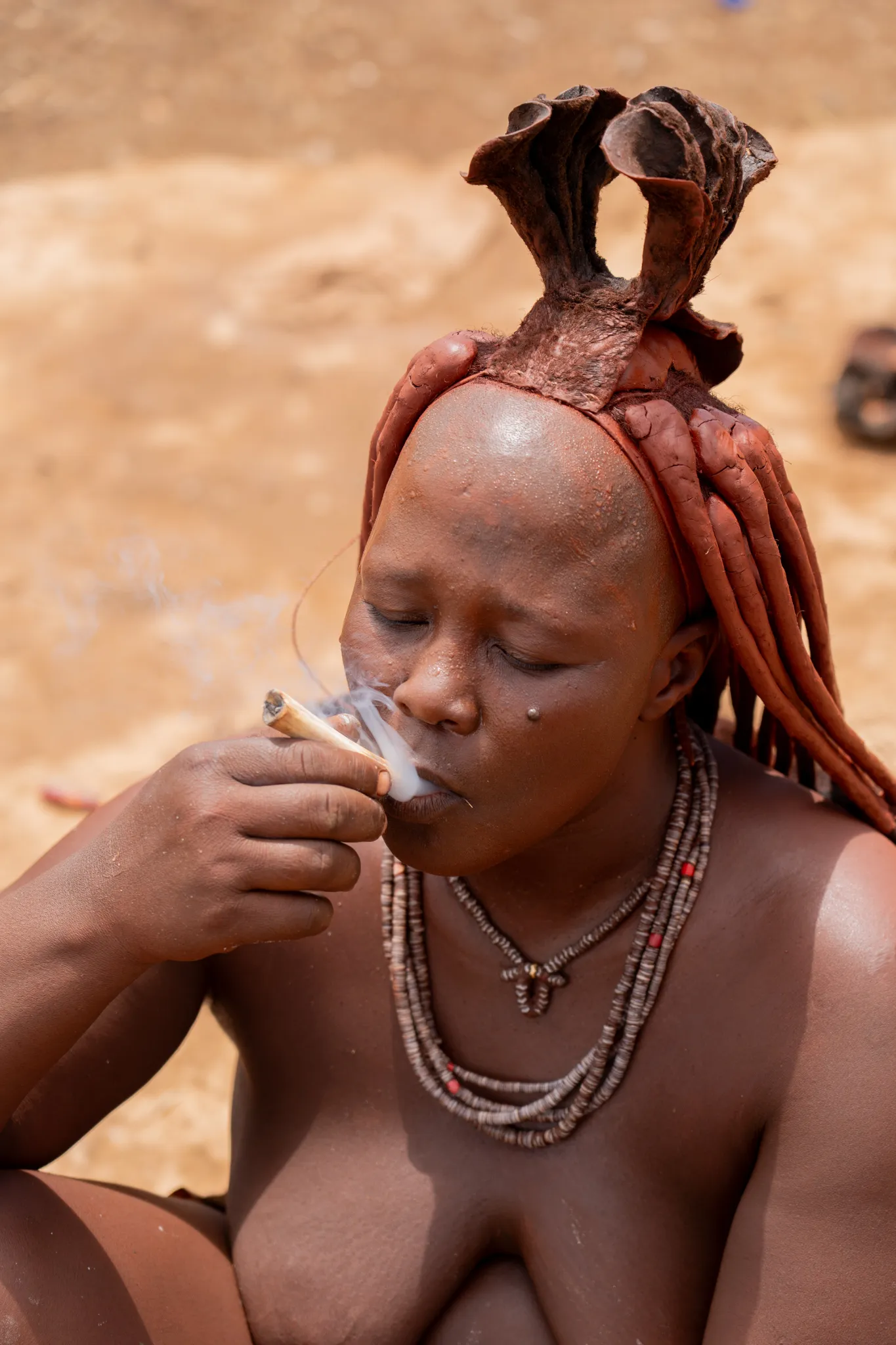 Himba woman smoking a goat leg pipe, Namibia